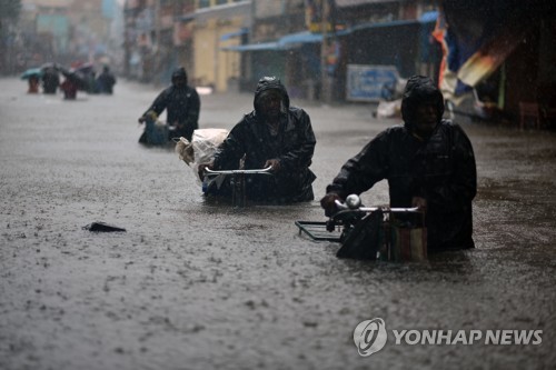 2021년 11월 11일 인도 첸나이시에 쏟아진 기록적인 폭우로 거리가 물에 잠기자 시민들이 허리까지 차오른 물을 헤치고 자전거를 끌고 가고 있다. 기후변화에 관한 정부 간 협의체(IPCC)에 따르면 지구온난화에 따른 해수면 상승으로 첸나이와 뭄바이 등 인도 해변 도시는 21세기말에 3피트(약 91.4cm) 가량 수몰될 전망이다. EPA=연합