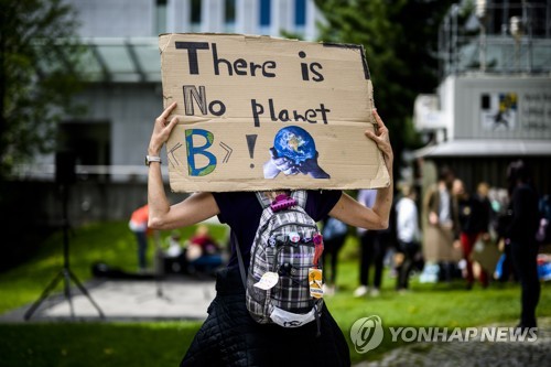 5월 26일 포럼이 열리는 동안 토론장 밖에서 한 기후 활동가가 '다른 지구는 없다'는 문구가 적힌 종이를 들고 시위를 벌이고 있다. EPA=연합