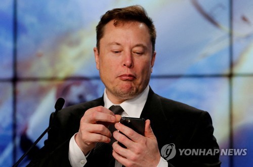 일론 머스크 테슬라 CEO가 한 행사장에서 자신의 휴대폰을 보고 있다. 연합=로이터 