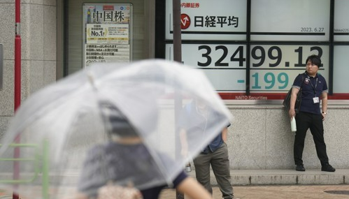 2023년 6월 27일 도쿄의 한 증권사에서 일본 닛케이225 지수를 보여주는 모니터 근처 교차로에서 보행자들이 서 있다. AP=연합