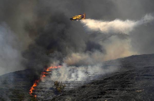 25일(현지시간) 산불이 발생한 그리스 로도스섬에서 비행기가 물을 뿌리며 진화 작업을 하고 있다. 사진=AP연합뉴스