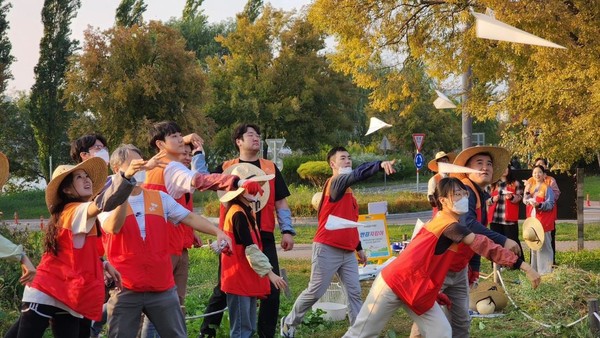 SK이노베이션 계열 구성원들이 물에 녹는 종이에 씨앗을 담은 '꽃씨 비행기'를 생태교란식물을 제거한 자리에 던지고 있다.   사진=SK이노베이션