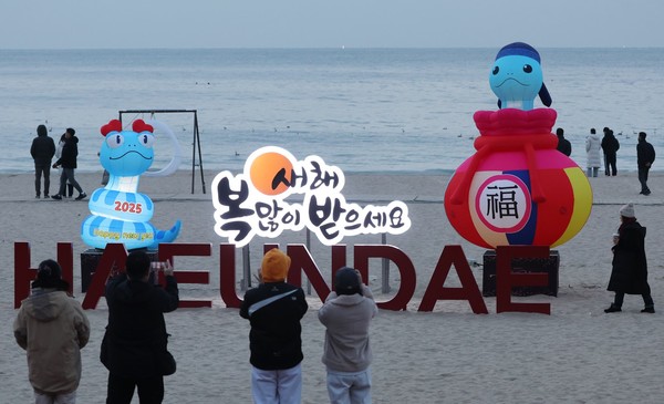 2025년 을사년 푸른 뱀의 해를 앞두고 30일 오전 부산 해운대해수욕장 백사장에 뱀 모양의 새해 상징조형물이 설치돼 시민들이 사진을 찍으며 추억을 남기고 있다. [연합뉴스]