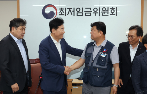 최저임금위원회 사용자위원 운영위원인 류기정 한국경영자총협회 전무(왼쪽 두 번째)와 근로자위원 운영위원인 류기섭 한국노총 사무총장(오른쪽 두 번째)이 10일 정부세종청사에서 최저임금에 합의한 뒤 악수하고 있다. 연합뉴스